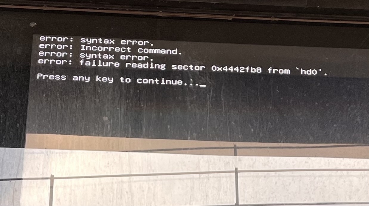 A tv screen outside a building with text reading “syntax error. Incorrect command. Syntax error. Failure reading sector and then a memory address. Press any key to continue “