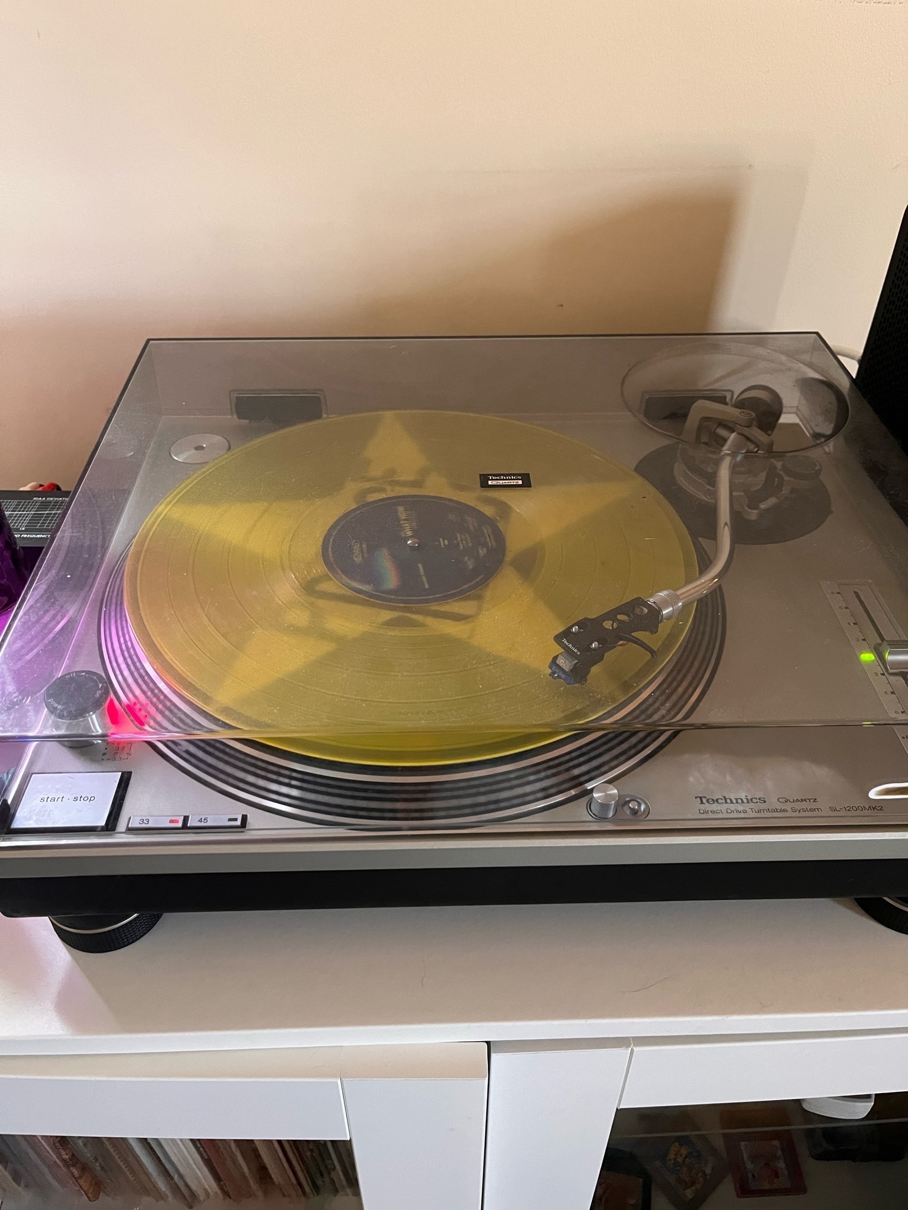 A record player with a clear yellow vinyl record playing on it. 