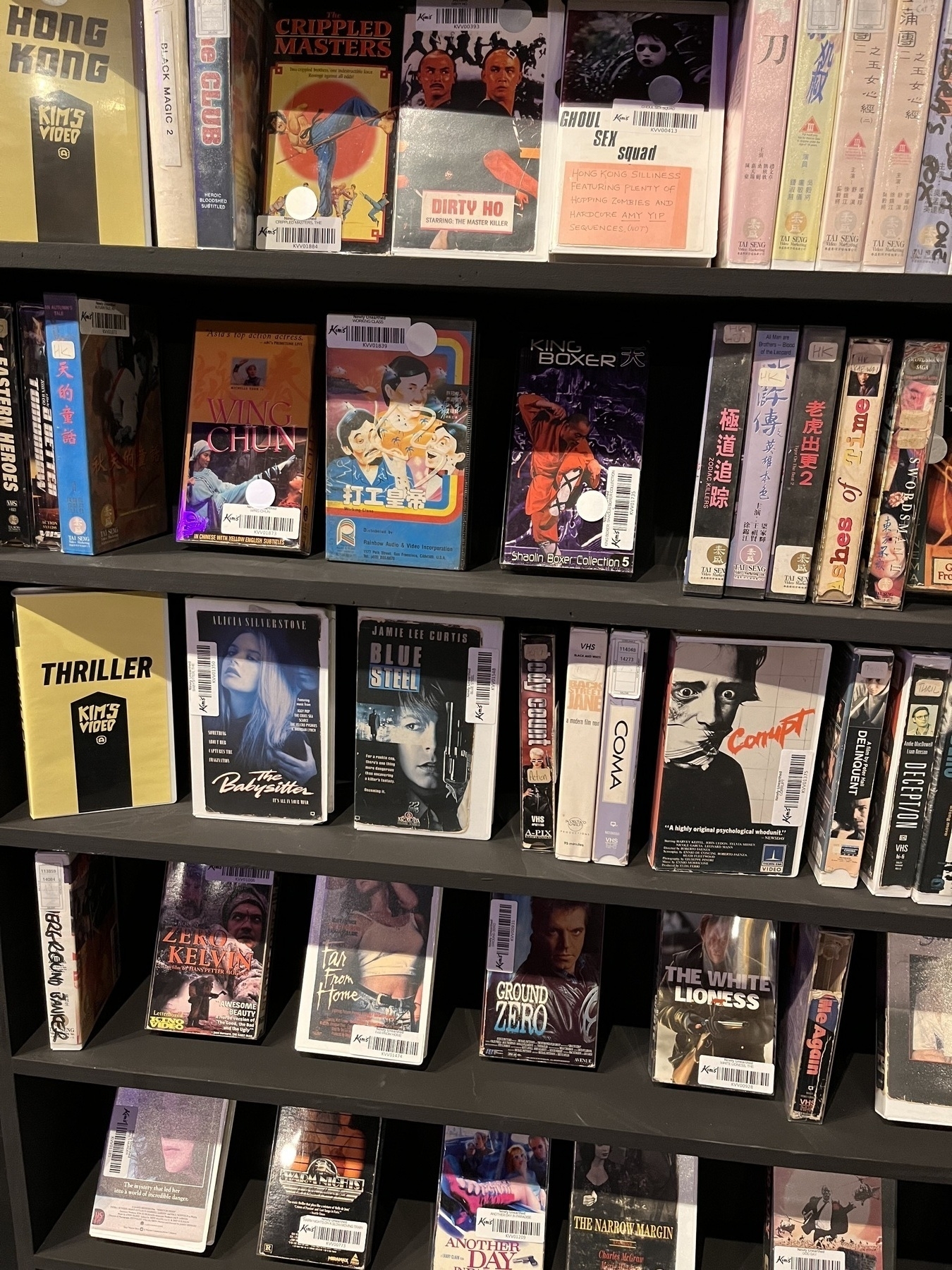 A shelf of VHS tapes, mostly obscure,B, or Japanese genre films. 