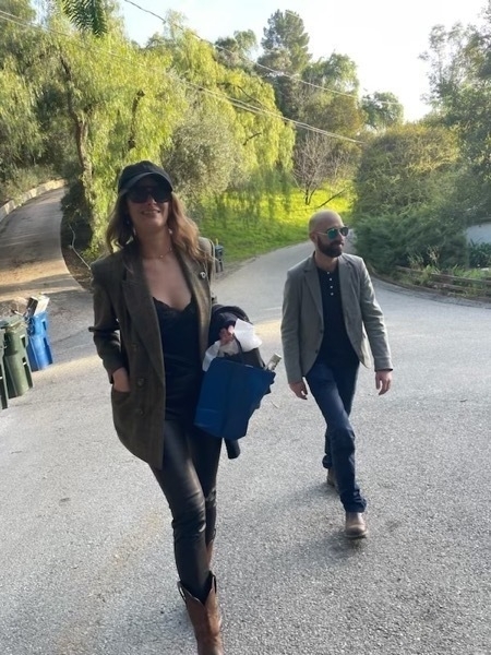 Two white people walk confidently towards the camera. The first, my cousin Karolina, is wearing dark sunglasses, a black baseball hat, leather pants, and a jacket. I'm behind her, wearing polarized sunglasses, dark jeans, and a grey balzer over a black half button. We look dope.