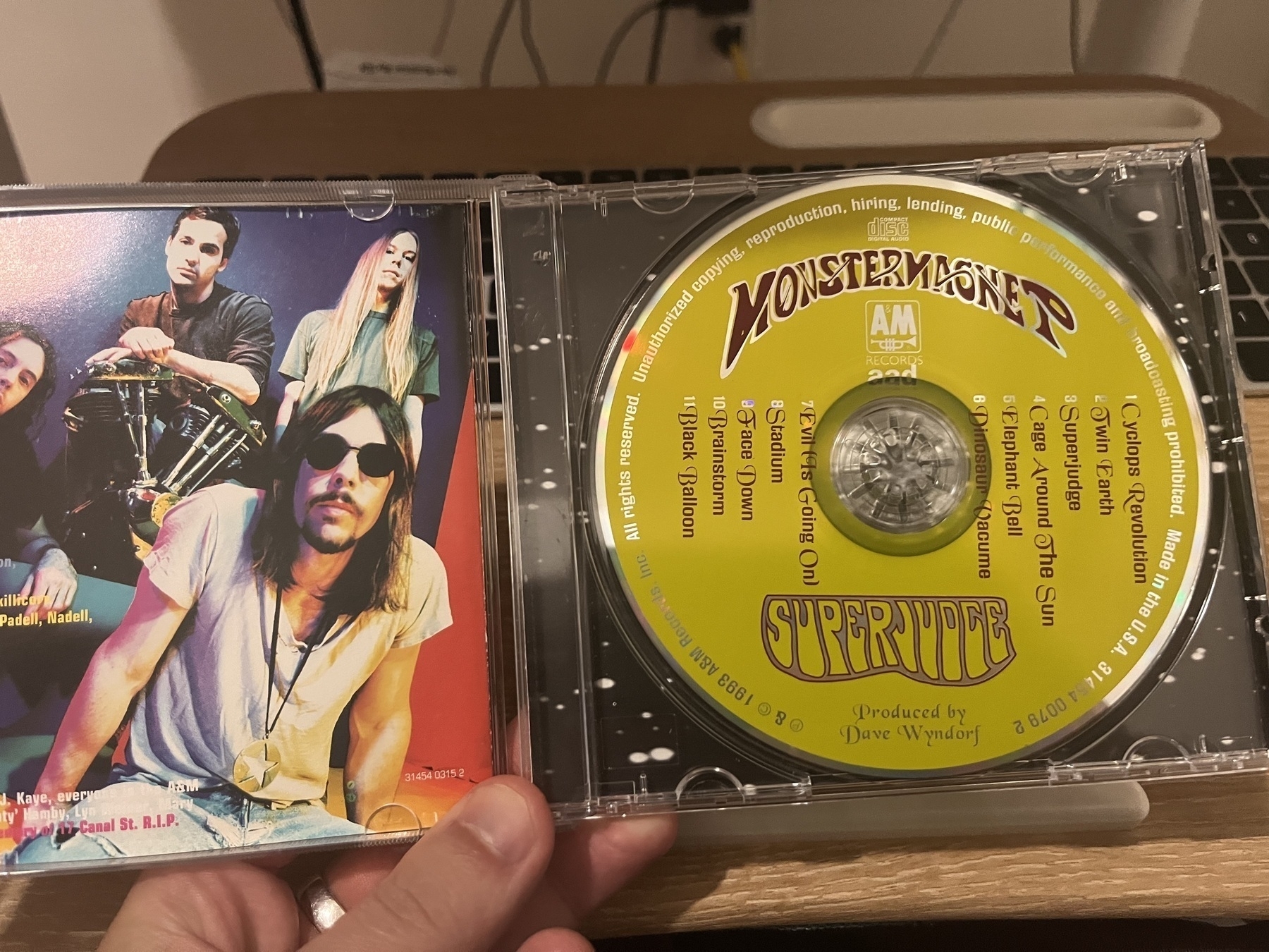 Auto-generated description: A hand holds an open CD case featuring the band Monster Magnet's album Superjudge.
